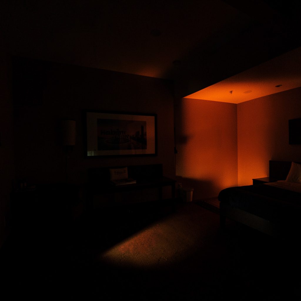 Moody photograph of a hotel courtyard at dusk, charcoal shadows and warm amber accents