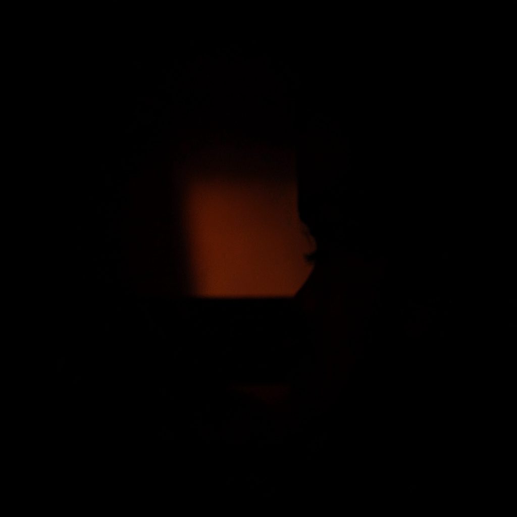 Quiet hotel lounge interior with warm beige seating and soft amber lighting, deep shadow at the edges, relaxed atmosphere.